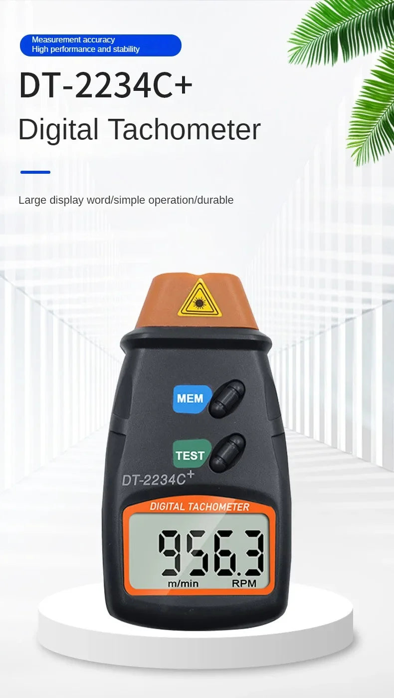A black digital tachometer with an orange display showing 9563 m/min RPM, displayed on a white surface.