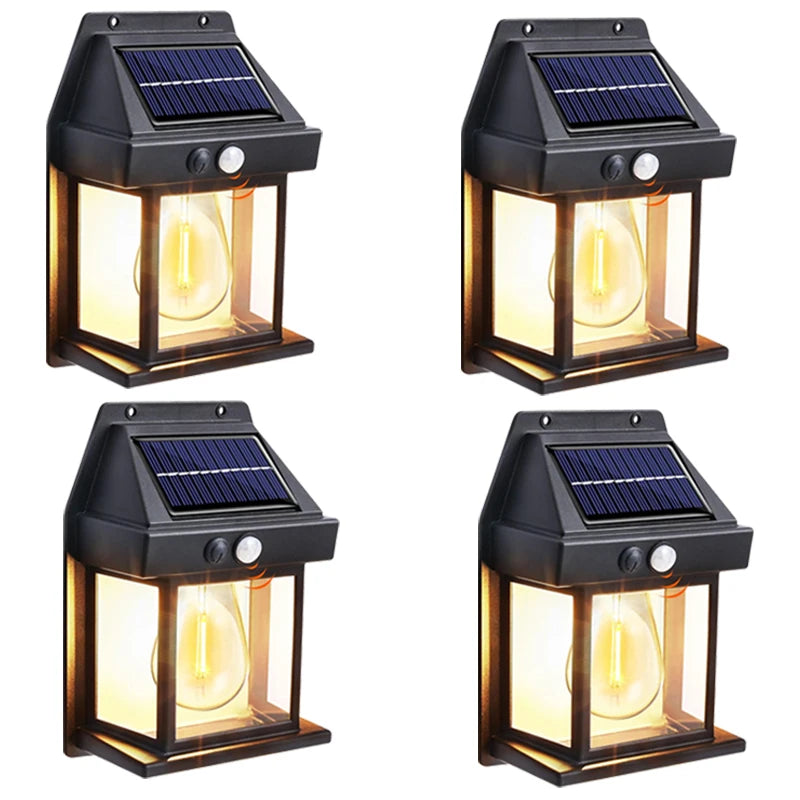 A set of four black solar motion sensor outdoor wall lights with glass globes and solar panels.