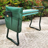 Dunkelgrüner, robuster Gartenknierhocker mit Metallrahmen im Freien.