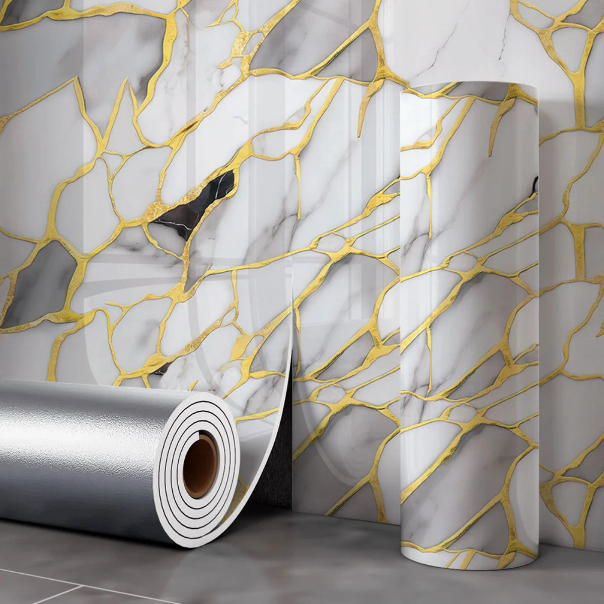 Autocollants muraux effet marbre argenté avec veinage doré sur mur gris.