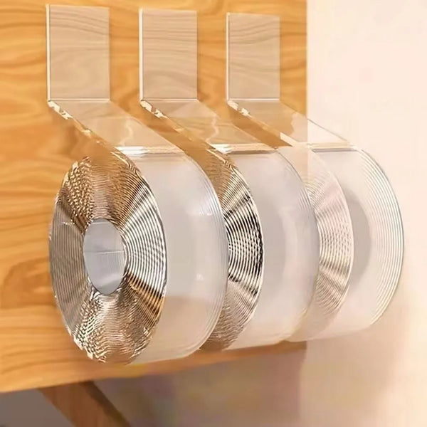 Three rolls of clear double-sided reusable adhesive tape are displayed on a wooden surface.