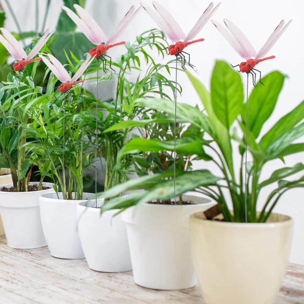A collection of realistic pink and red dragonfly clips used for garden decor, planted in white pots.