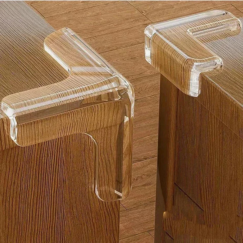 A close-up of a silicone corner edge protector for baby safety, featuring clear silicone guards on a wooden cabinet.