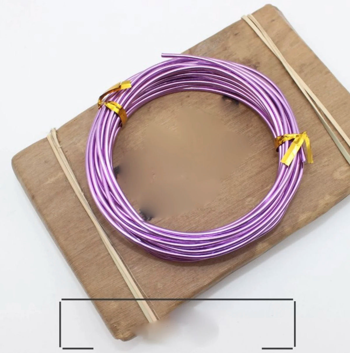 Violettes anodisiertes Metall-Schmuckdraht, auf einem Holzbrett mit dünnen Bambusstäbchen gewickelt.
