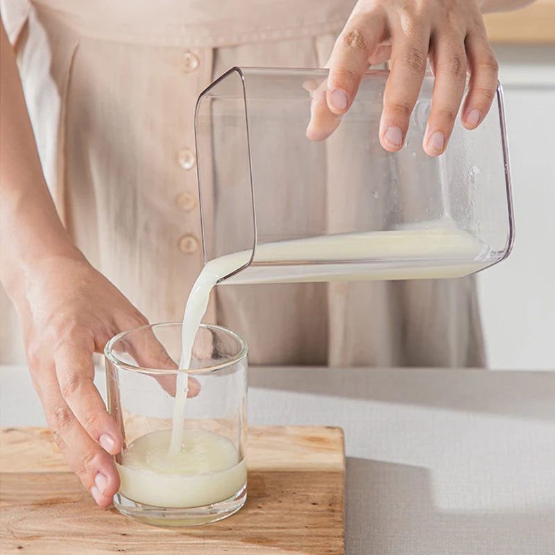 Eine Hand gießt weißen Joghurt oder Whey aus einem Edelstahlfilter in ein Glasgefäß.