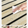 Hand wiping water droplets off a wood grain wall panel with a white cloth, demonstrating durability and waterproof features.
