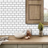 A close-up of a kitchen countertop featuring white subway tiles, a bowl of eggs, and a wooden cabinet.