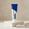A tube of Wall Repair Paste in blue and white packaging is displayed on a light wooden block.