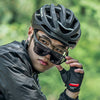 A person wearing a black helmet and sunglasses is looking directly at the camera in an outdoor setting.