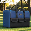 A blue and black heavy duty multi-compartment tool organizer bag resting on green grass.