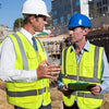 Two construction workers wearing high-visibility safety vests discussing a project.