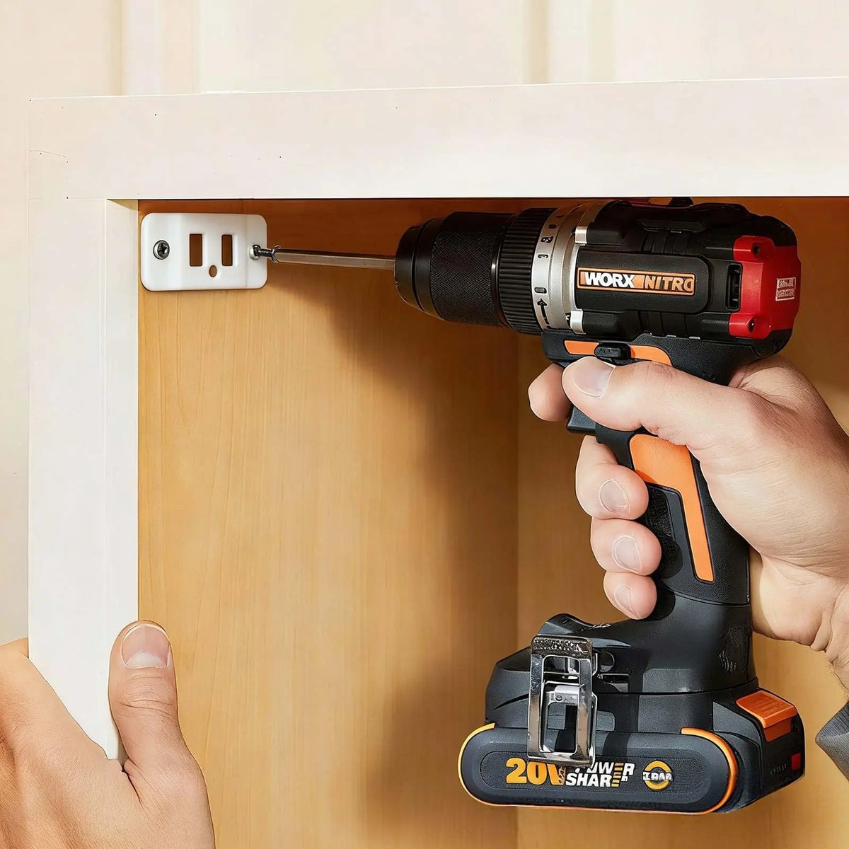 A hand is using a WORX NITRO power drill to install heavy-duty stainless steel corner brackets into a wooden cabinet frame.