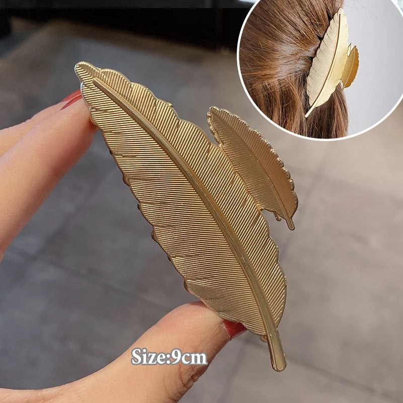 Elegant gold S-shaped metal hair clips shown being held by a hand with an inset showing the clip placement.