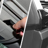Une main interagit avec un clip de fixation en plastique noir sur un élément de garniture de voiture gris.