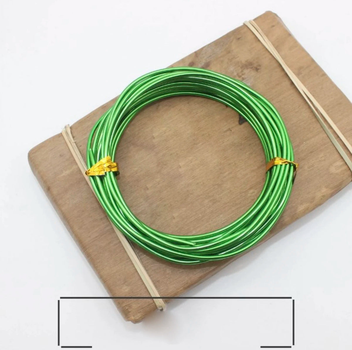 Grünes anodisiertes Metall-Jewelry-Draht, auf einem Holzbrett mit Schnur gewickelt.