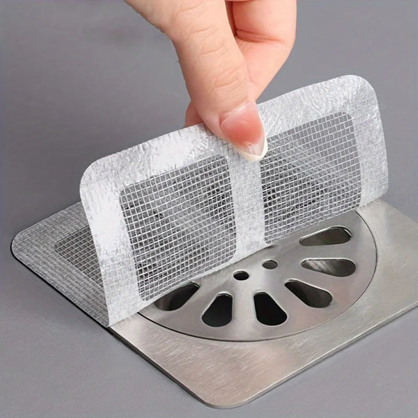 A hand is placing a reusable mesh strainer filter over a metal drain grate.