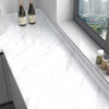 A white marble countertop with a window view and two bottles of wine on the surface.
