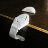A set of six white silicone safety clips for doors and drawers resting on a dark wooden surface.