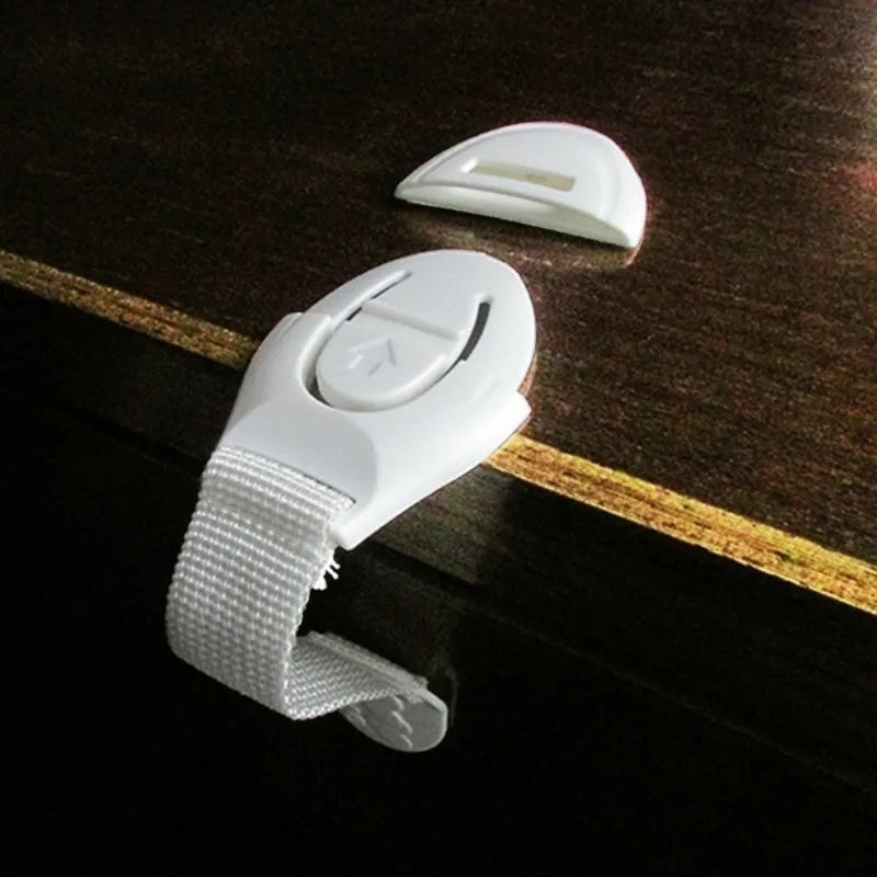 A set of six white silicone safety clips for doors and drawers resting on a dark wooden surface.