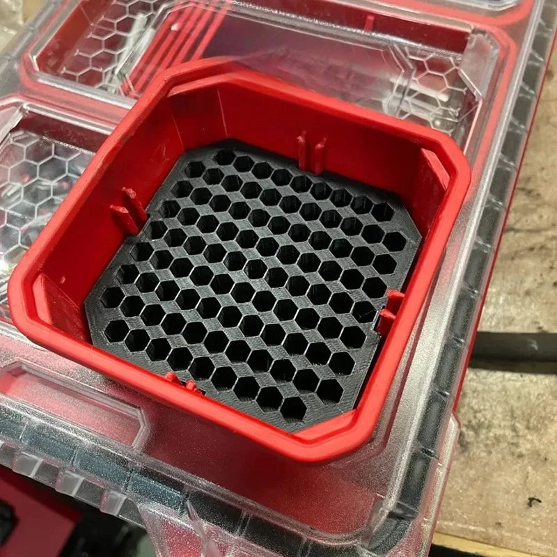 Red plastic organizer insert with a honeycomb grid for storing drill bit or screwdriver bits