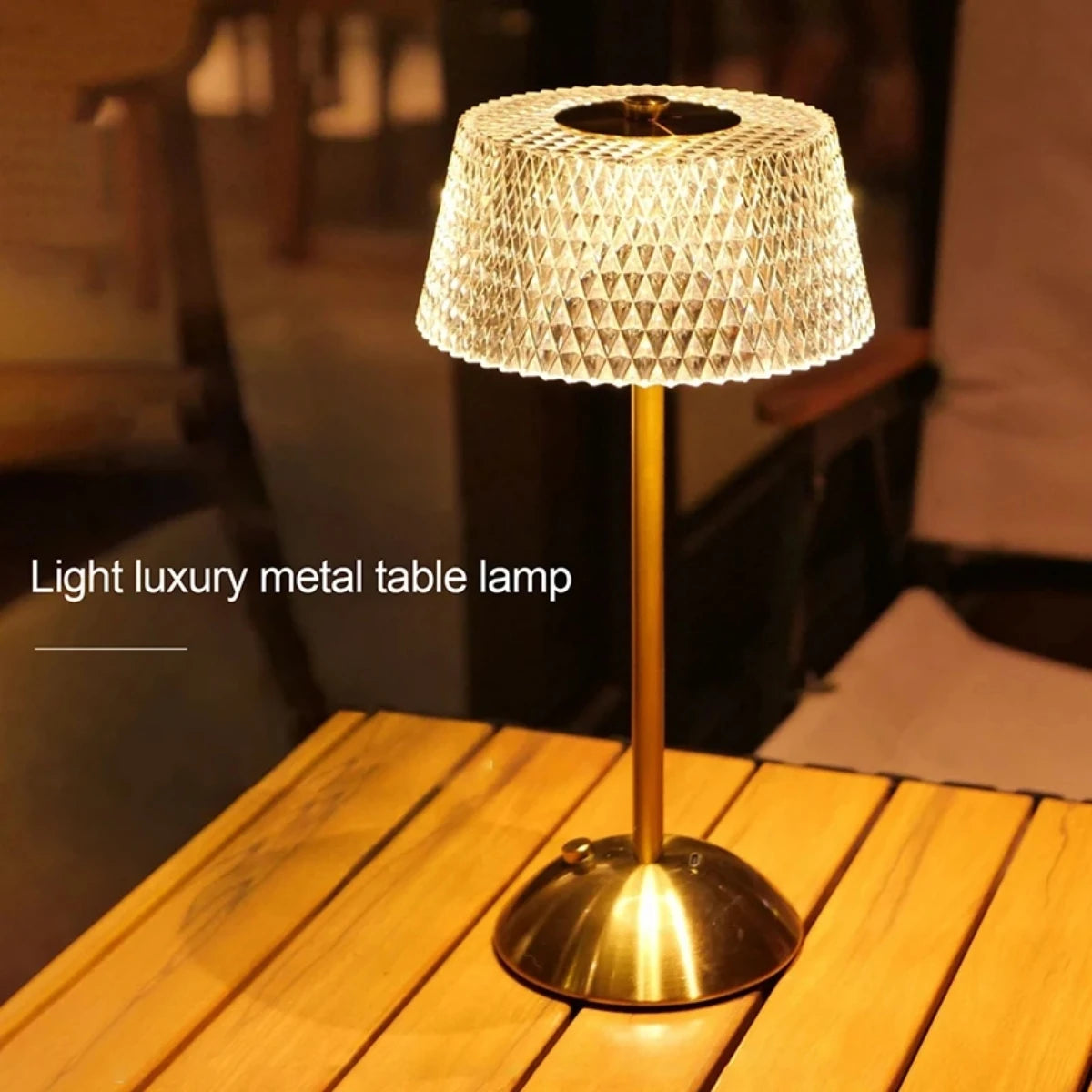 A gold metal table lamp with a textured shade sits on a wooden surface.