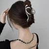 A close-up of a woman's dark hair styled in an updo with elegant gold S-shaped metal hair clips.