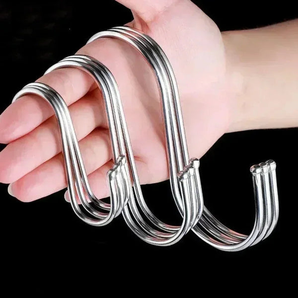 A hand holds a set of shiny stainless steel hanging hooks.