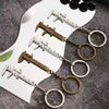 A set of precision metal jewelry measuring rulers and calipers with circular jump rings displayed on a dark surface.