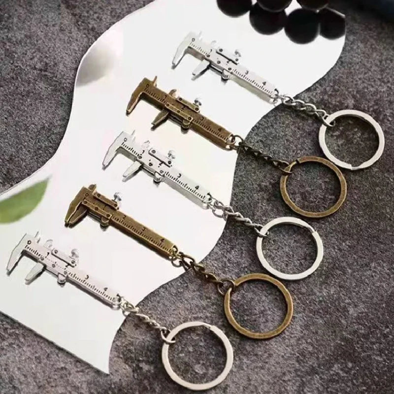 A set of precision metal jewelry measuring rulers and calipers with circular jump rings displayed on a dark surface.