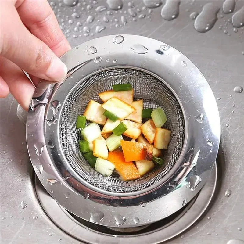 A hand is placing diced fruit into a stainless steel sink strainer drain filter mesh under running water.