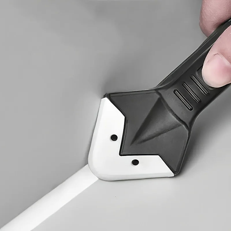 Une main tient un kit d'outil de calfeutrage en silicone noir et blanc pour retirer des joints sur une surface grise.