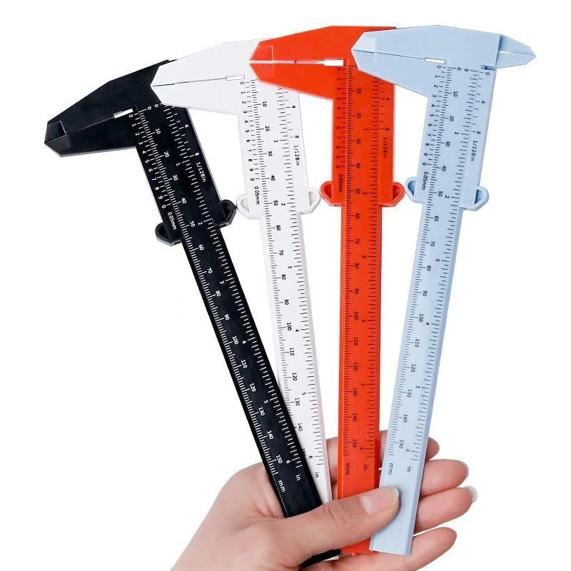 A set of five precision plastic vernier calipers in black, white, orange, and light blue are held in a hand.