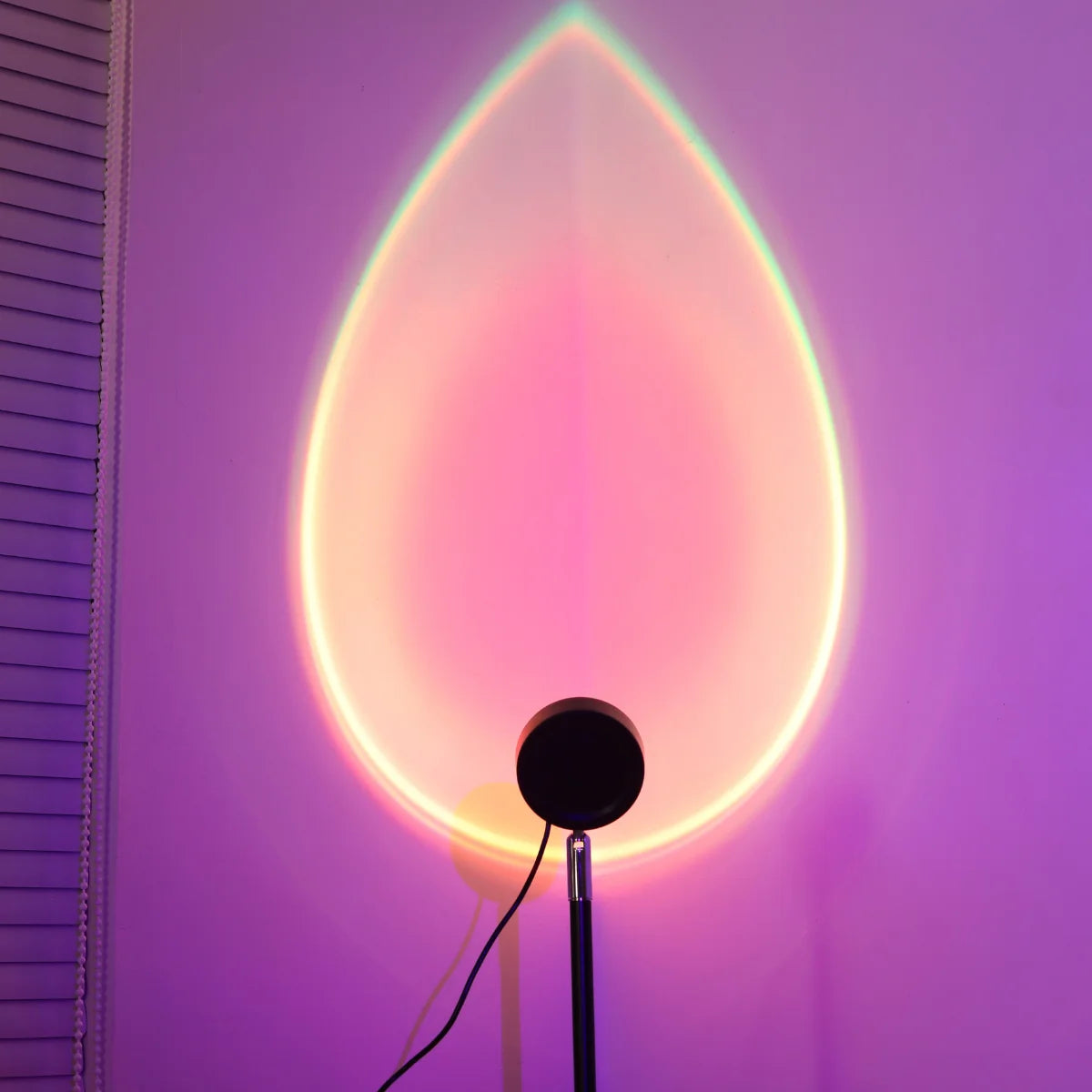 Lumière de nuit en forme de goutte, rose et orange, projetée sur un mur violet.