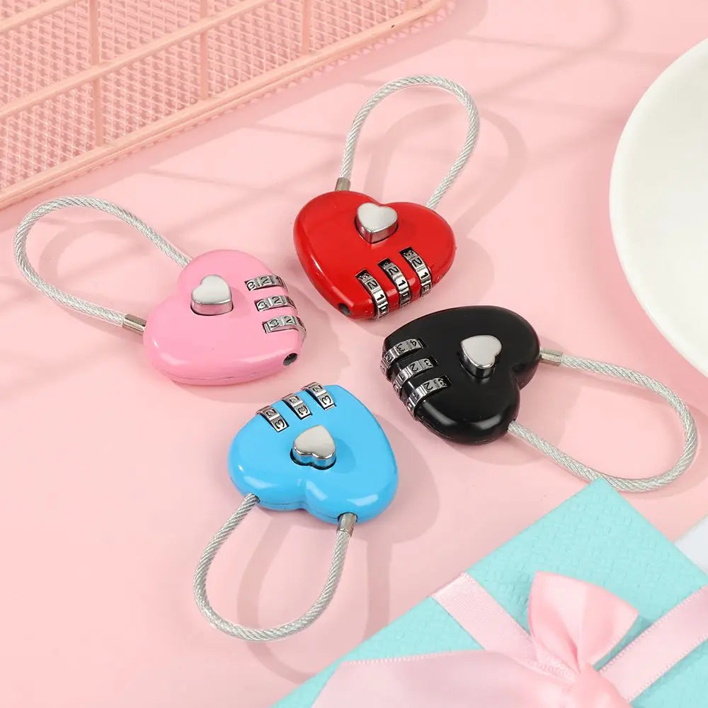 Three heart-shaped combination locks in red, pink, and black with silver accents displayed on a light pink background.