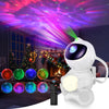 A white astronaut-shaped LED star projector night light illuminates a vibrant purple and pink galaxy display.