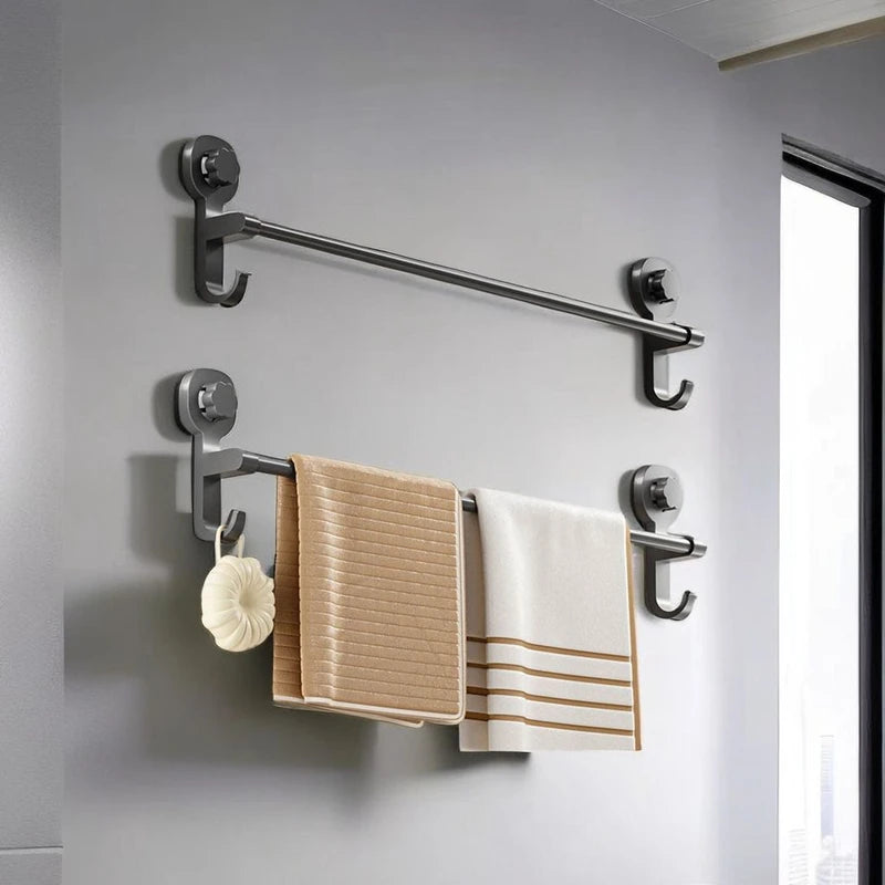 A silver towel rack mounted on a gray wall with two beige towels hanging from it.