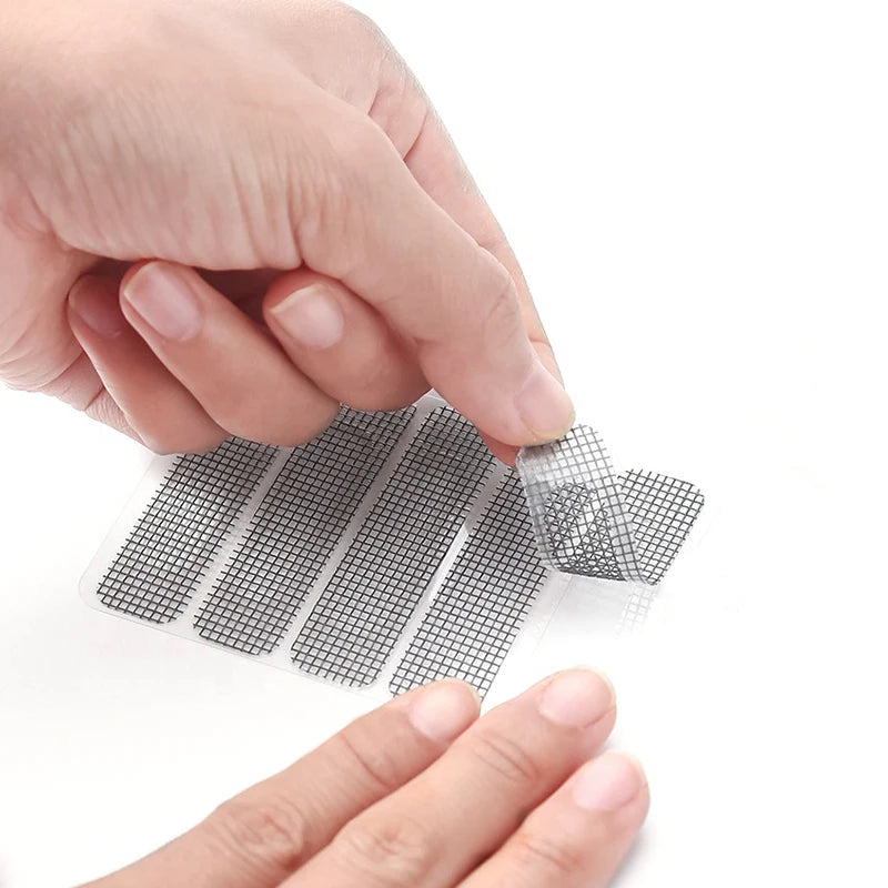 A hand is applying a window screen repair patch kit to a glass surface.