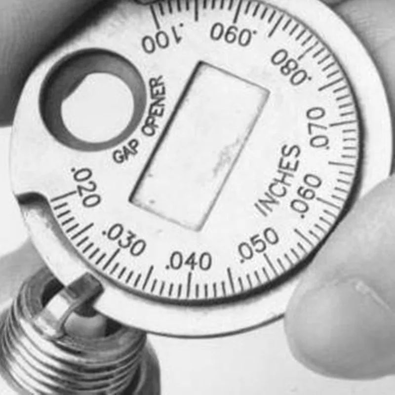 A close-up photo of a precision spark plug gap gauge set with a graduated scale and a gap opener tool.