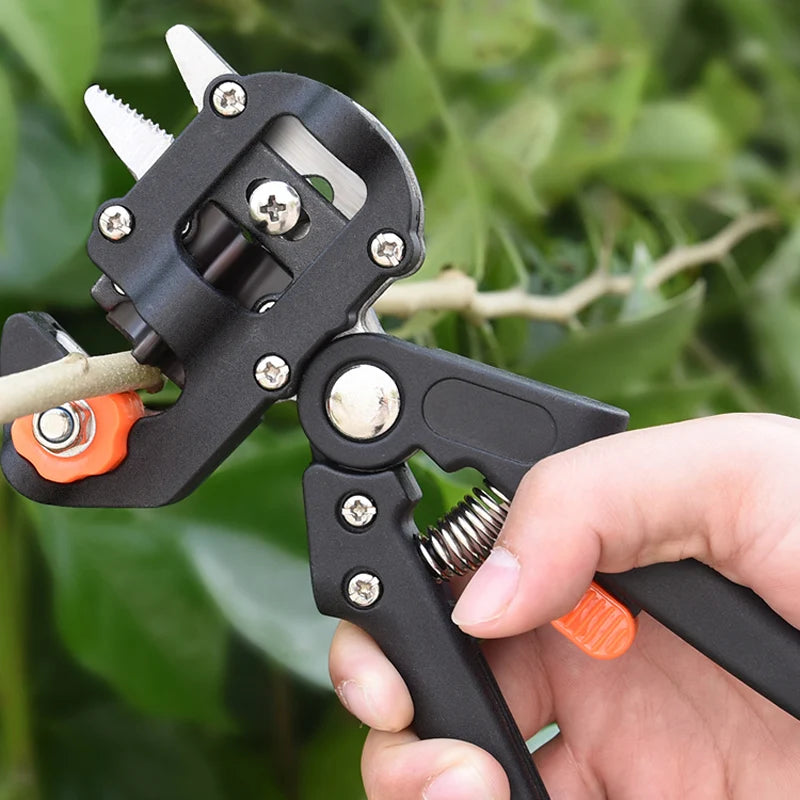 A hand holds a black professional grafting and pruning set tool with sharp blades and a wire cutter.