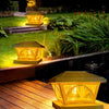 A close-up of a yellow solar LED post cap light illuminating a garden pathway at night.