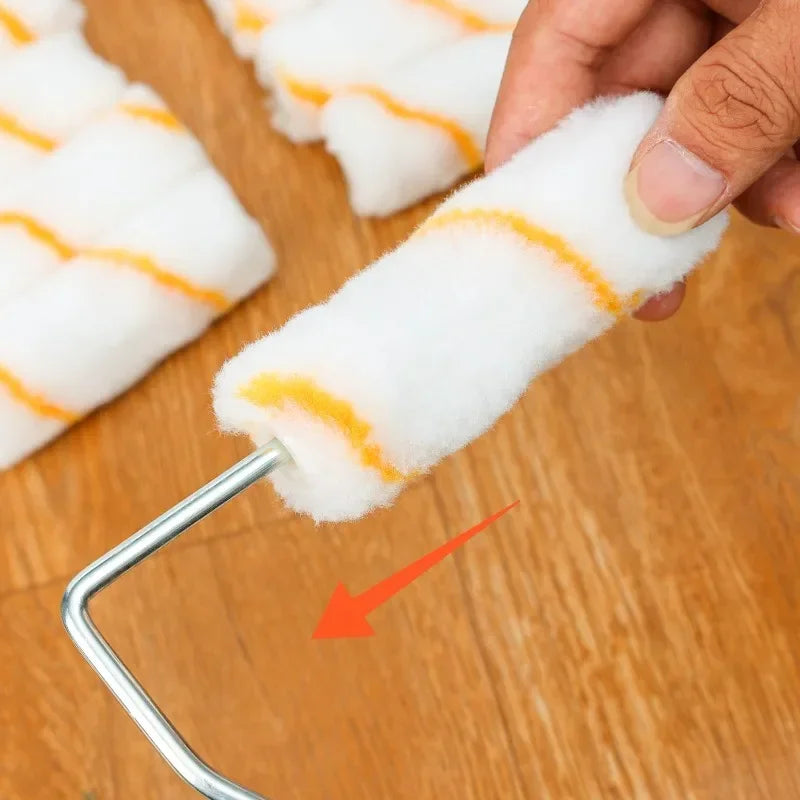 Una mano sostiene un rodillo de espuma blanco con rayas naranjas, demostrando la aplicación de un kit de rodillo para pintura