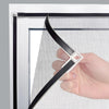 A hand is holding a black magnetic window screen, demonstrating its installation or use in a window frame.