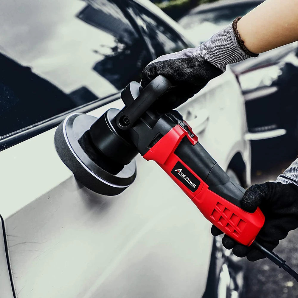A hand wearing a glove is using a red compound buffing polishing pad on a car's exterior.