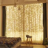 Una ventana decorada con luces de hadas blancas transparentes creando un efecto de cortina brillante y luminosa.