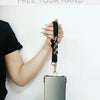 A hand is holding a black braided lanyard attached to a smartphone, demonstrating the product.