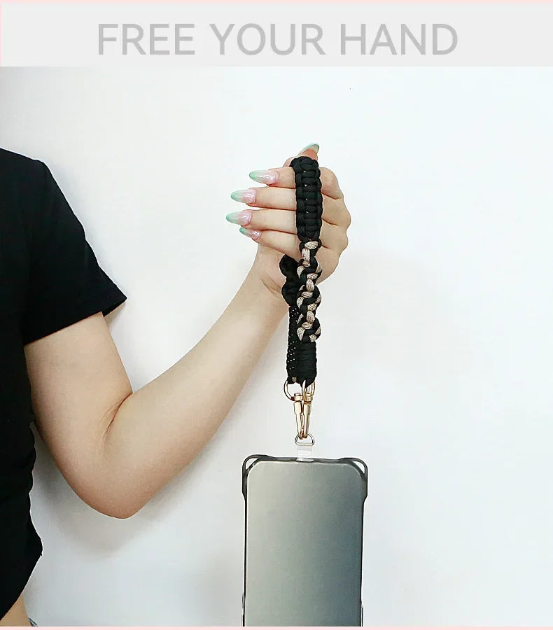 A hand is holding a black braided lanyard attached to a smartphone, demonstrating the product.