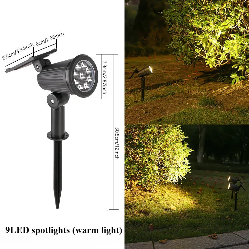 Schwarze Solar-LED-Spotleuchte auf einem Pol, die einen grünen Gartenzaun beleuchtet.