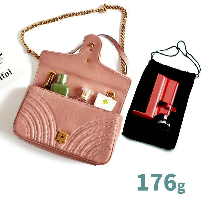 Bolsa de cuero rosa con correa de cadena dorada y bolsa de tela negra que contiene una cerradura de seguridad para puertas po