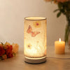 A retro style table lamp with a fabric shade glowing warmly, featuring a butterfly design.
