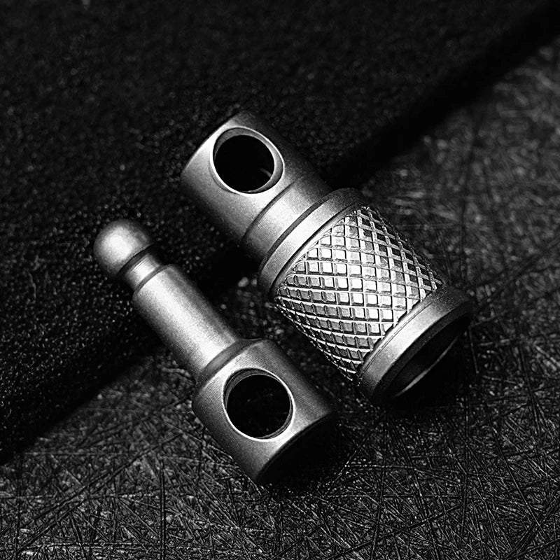 A close-up, black and white photo of a titanium alloy keychain key holder with a textured surface.